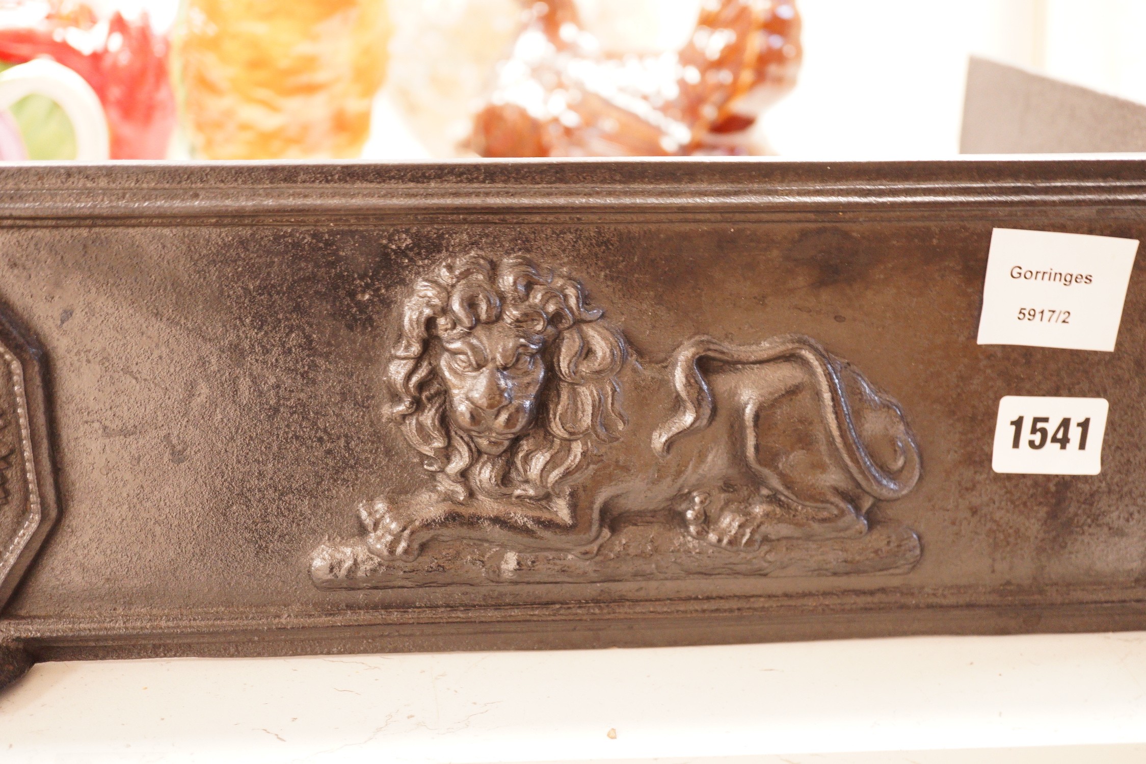 A blackened cast iron fender, of rectangular form decorated with lions, 76.5cm wide, 31cm deep